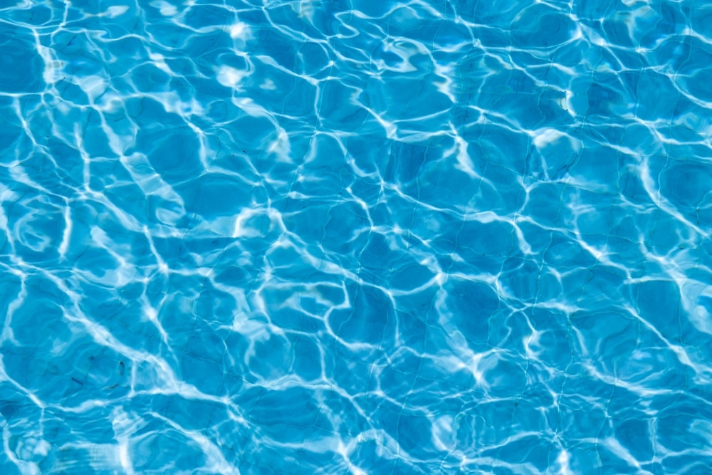 Eau de Piscine Bleue : Reflets de Soleil et Ondulations Eau de piscine bleue cristalline avec reflets du soleil et ondulations lumineuses apaisantes.
