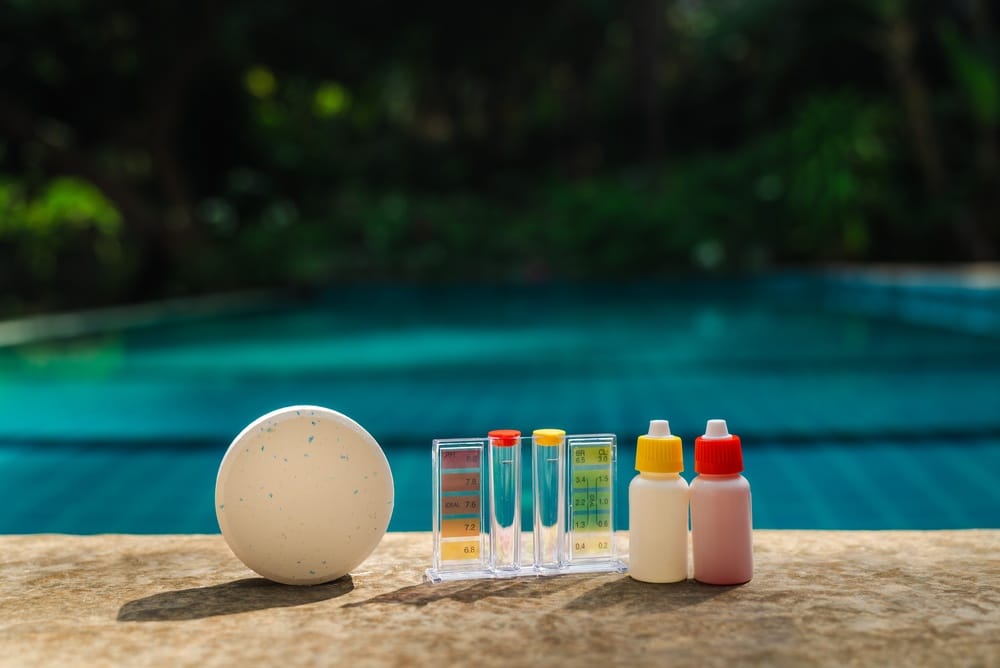 Entretien Piscine : Kit d'Analyse pH et Galet de Chlore Galet de chlore et kit d'analyse pH/chlore au bord d'une piscine pour l'entretien et le contrôle de l'eau.