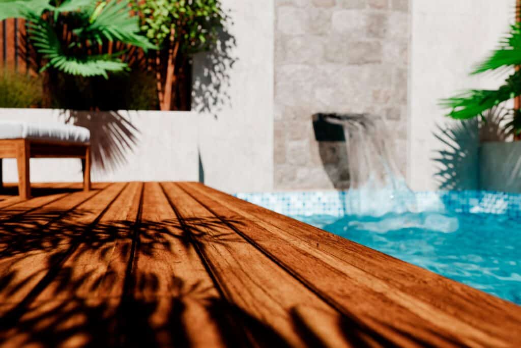 Terrasse en bois moderne avec piscine et cascade d'eau Terrasse en bois avec ombres de palmiers au bord d'une piscine avec cascade dans un jardin tropical ensoleillé.